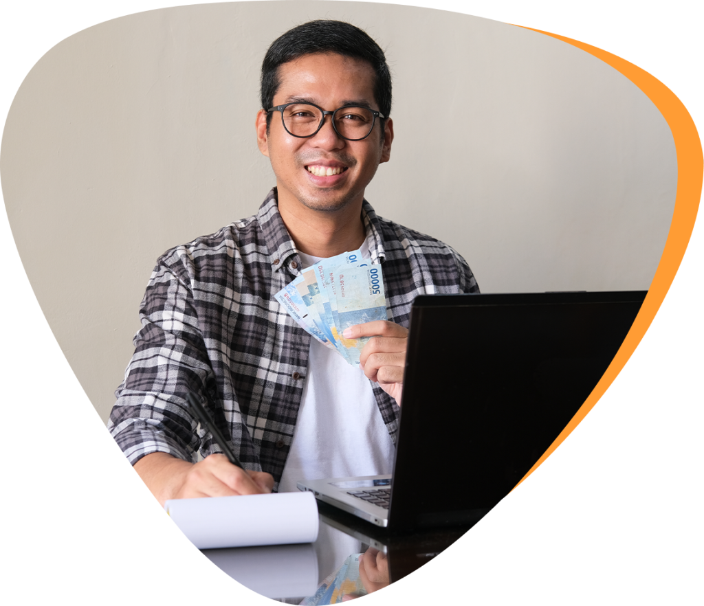 man in front of a laptop holding money